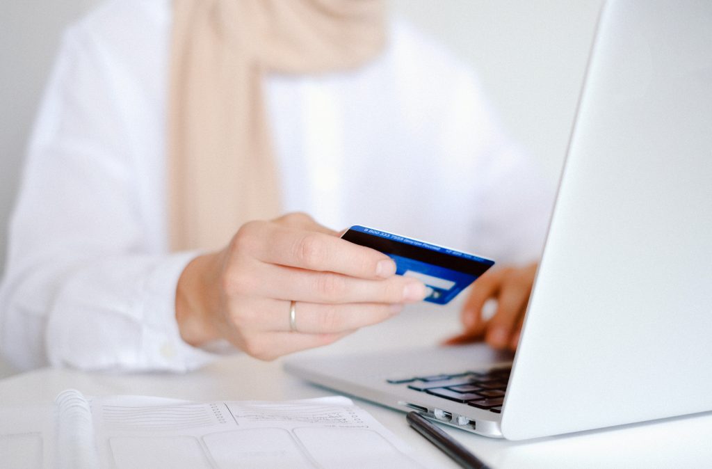 Person holding a credit card at a laptop